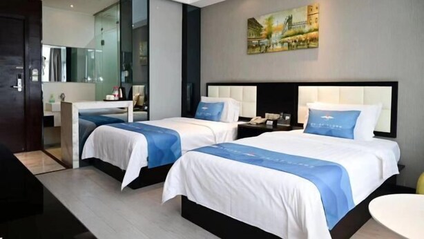 Ein Hotelzimmer mit zwei Betten, einem Schreibtisch, einem Stuhl und einem Bild an der Wand.