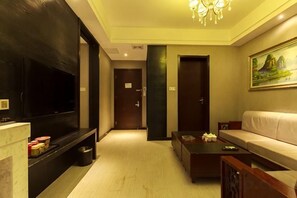 A hotel room with a flat-screen TV, a sofa, a coffee table, and a painting on the wall. - Yicheng Hotel (Henan University of Technology) (Zhengzhou)