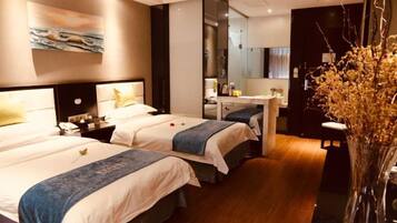 Habitación de hotel con dos camas, un escritorio, un espejo y un jarrón con flores secas.