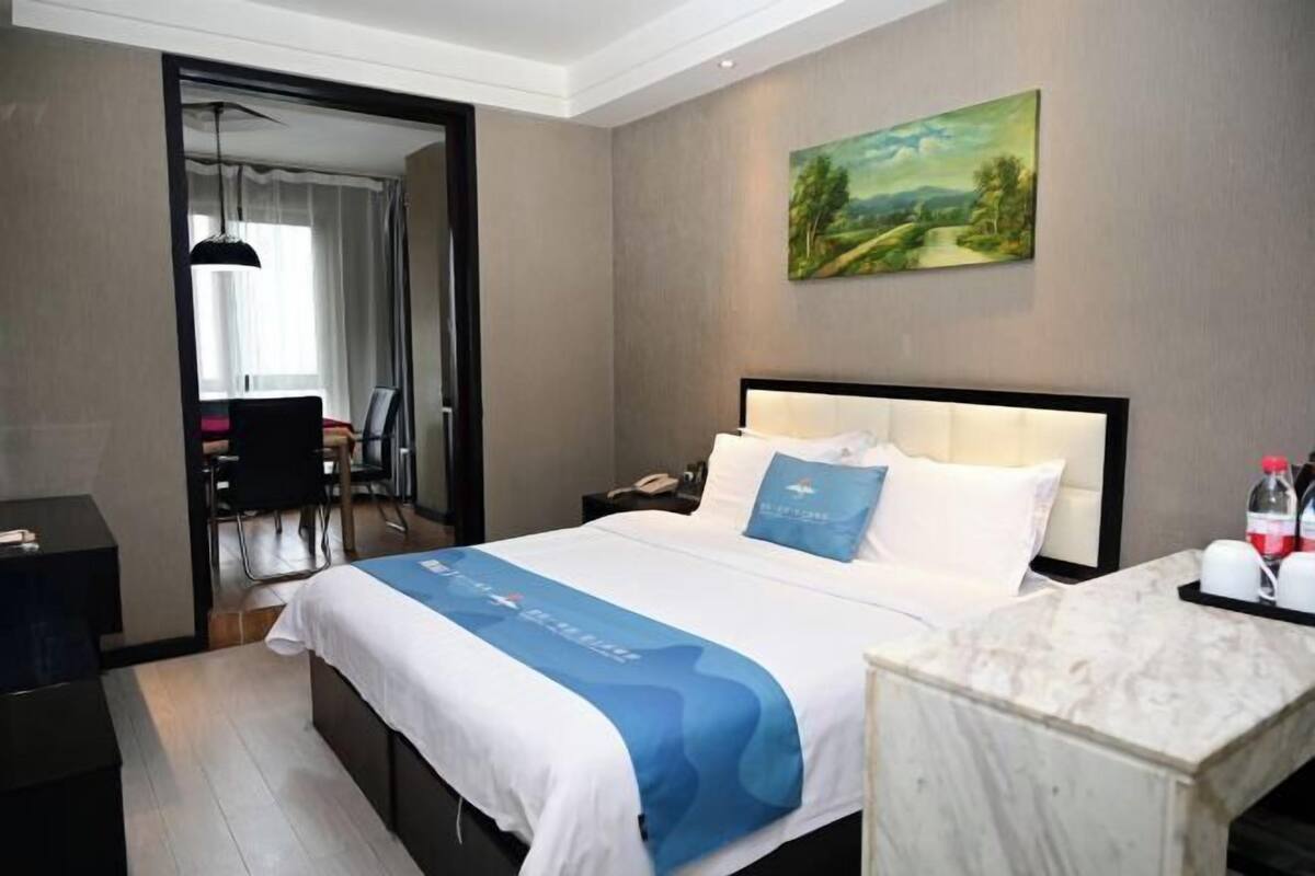 Habitación de hotel con cama, escritorio, silla, un cuadro en la pared y vistas al exterior.