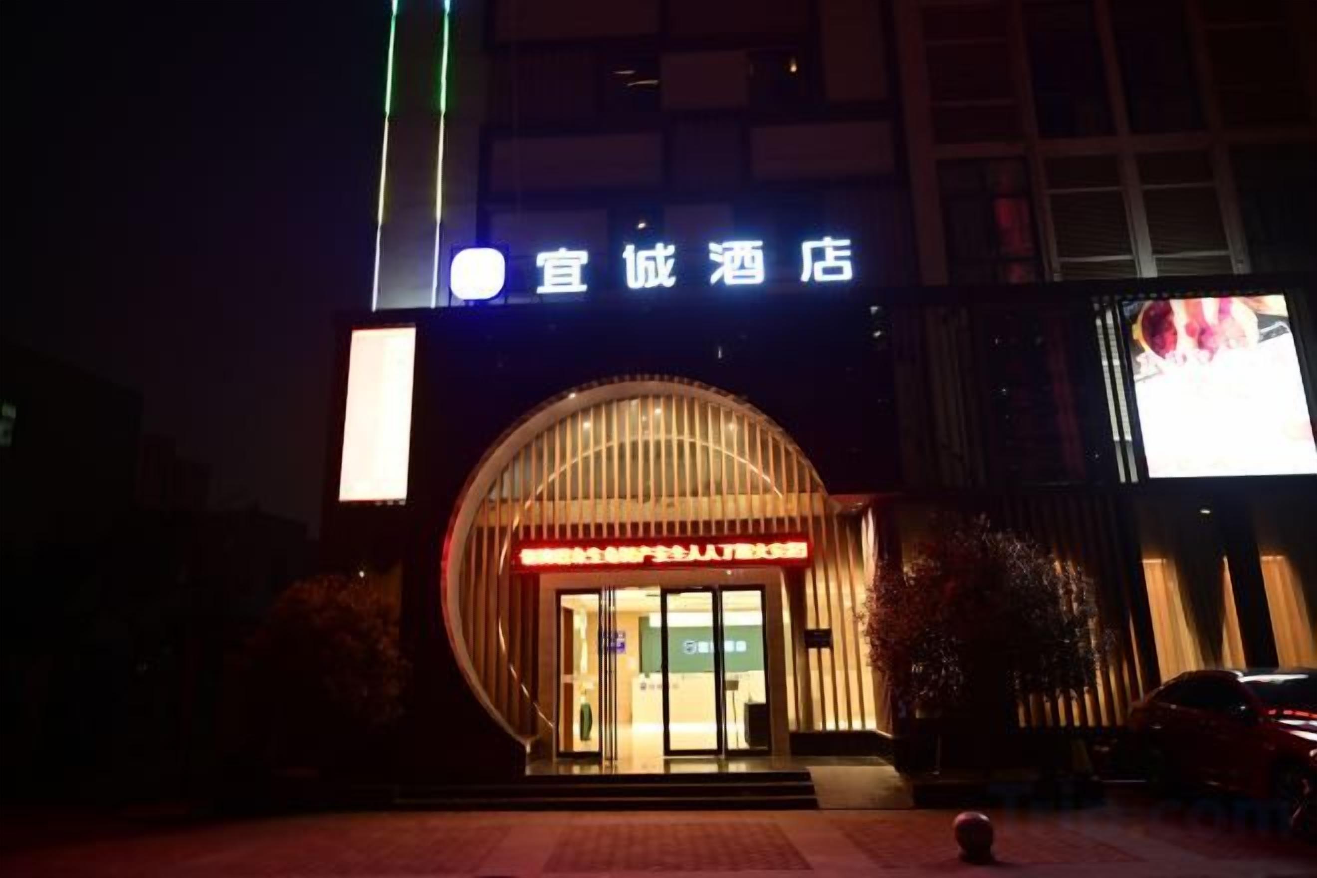 A hotel entrance with a large illuminated sign, a curved facade, and a visible entrance door.