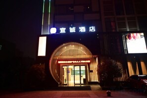 A hotel entrance with a large illuminated sign, a curved facade, and a visible entrance door. - Yicheng Hotel (Henan University of Technology) (Zhengzhou)
