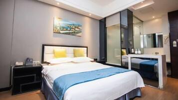 A modern hotel room with a large bed, bedside tables, a desk, and a large mirror.