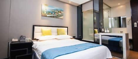 A modern hotel room with a large bed, bedside tables, a desk, and a large mirror.