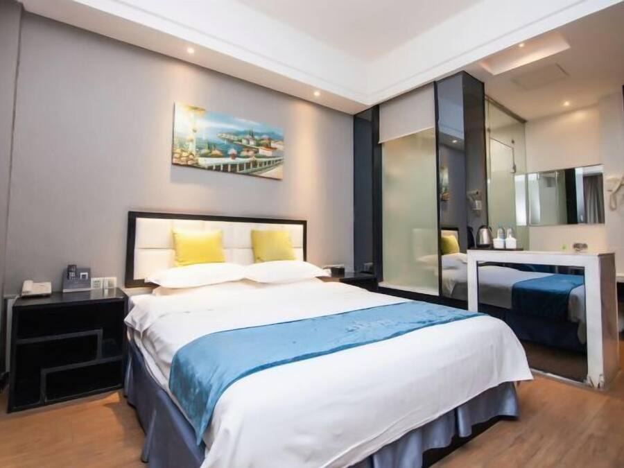 A modern hotel room with a large bed, bedside tables, a desk, and a large mirror.