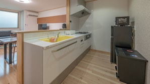 A compact kitchen with a central island, a built-in oven, and a refrigerator. - Takayama Stay Karatachi DX-A (Takayama)