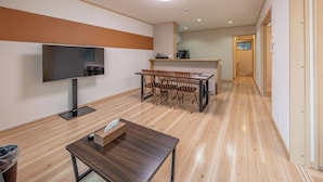A modern living room with a flat-screen TV, wooden dining table, and chairs. - Takayama Stay Karatachi DX-A (Takayama)