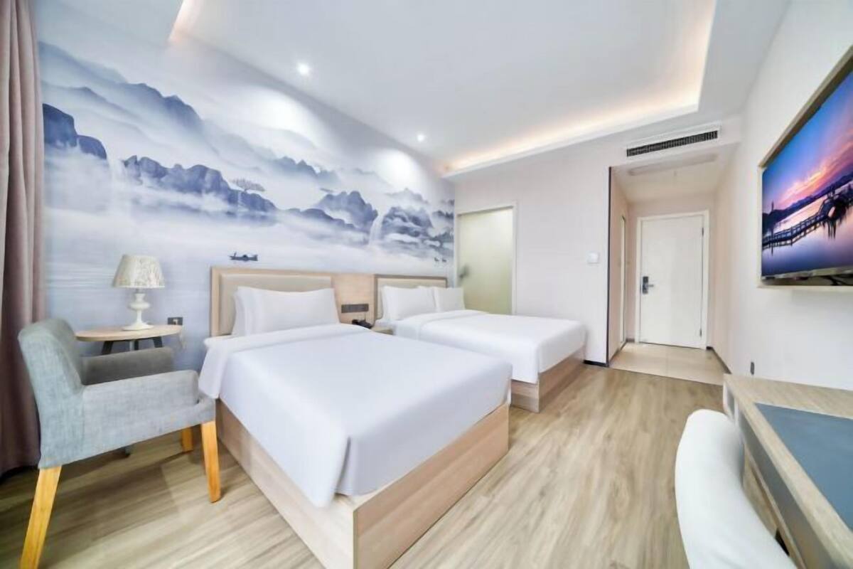 Ένα δωμάτιο ξενοδοχείου με δύο κρεβάτια, ένα γραφείο, μια καρέκλα, μια τηλεόραση και μια τοιχογραφία.
