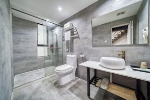 A modern bathroom with a glass-enclosed shower, a white toilet, and a large sink with a mirror above it. - Hangzhou Luming Linshe Hotel (Qingchun Square Subway Station) (Hangzhou)