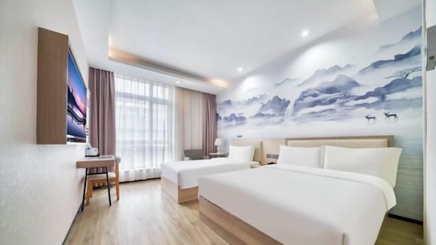 Une chambre d’hôtel avec deux lits, un bureau et une grande fresque murale.