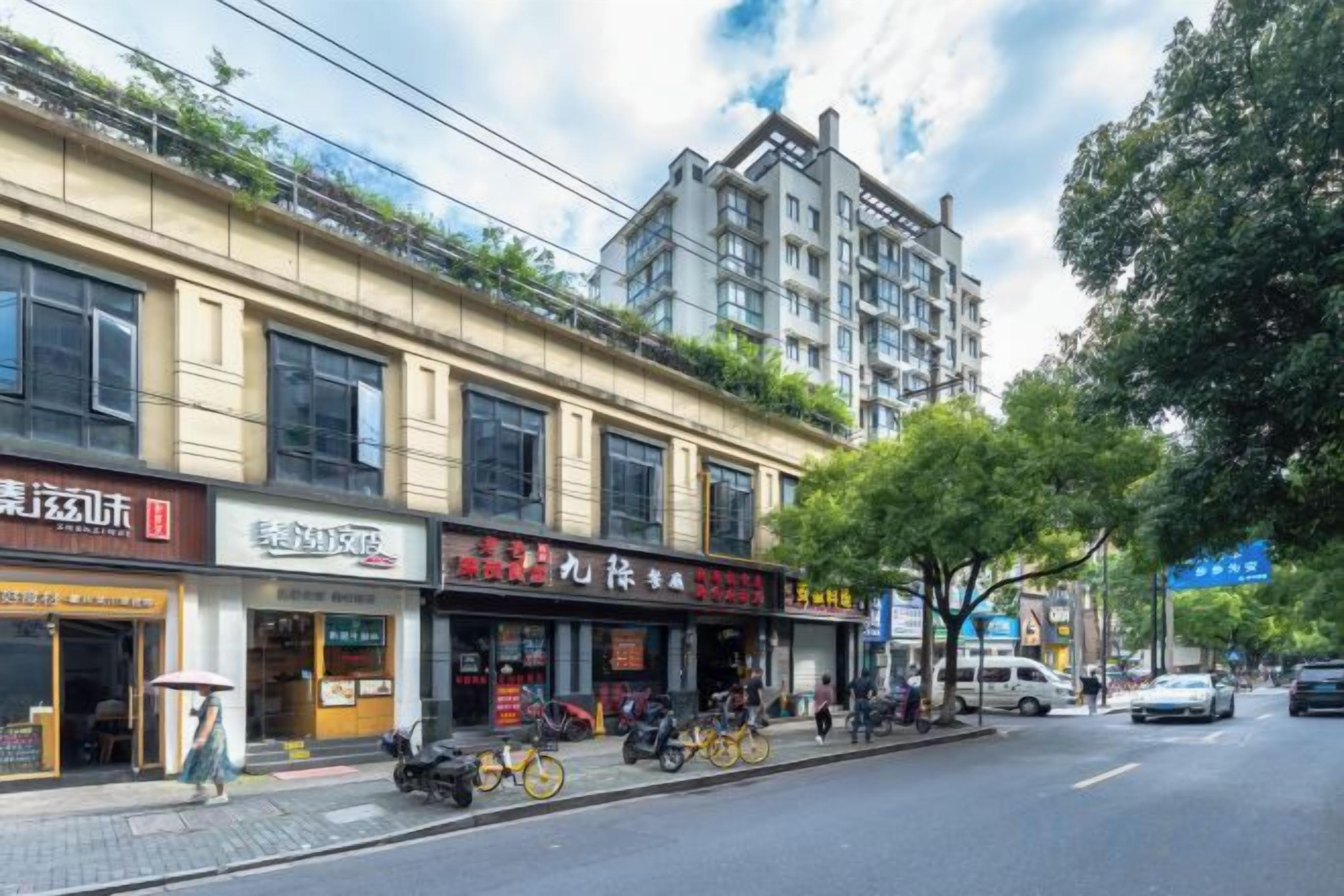 Vista de la calle con una hilera de tiendas, una bicicleta estacionada y un edificio con balcón.