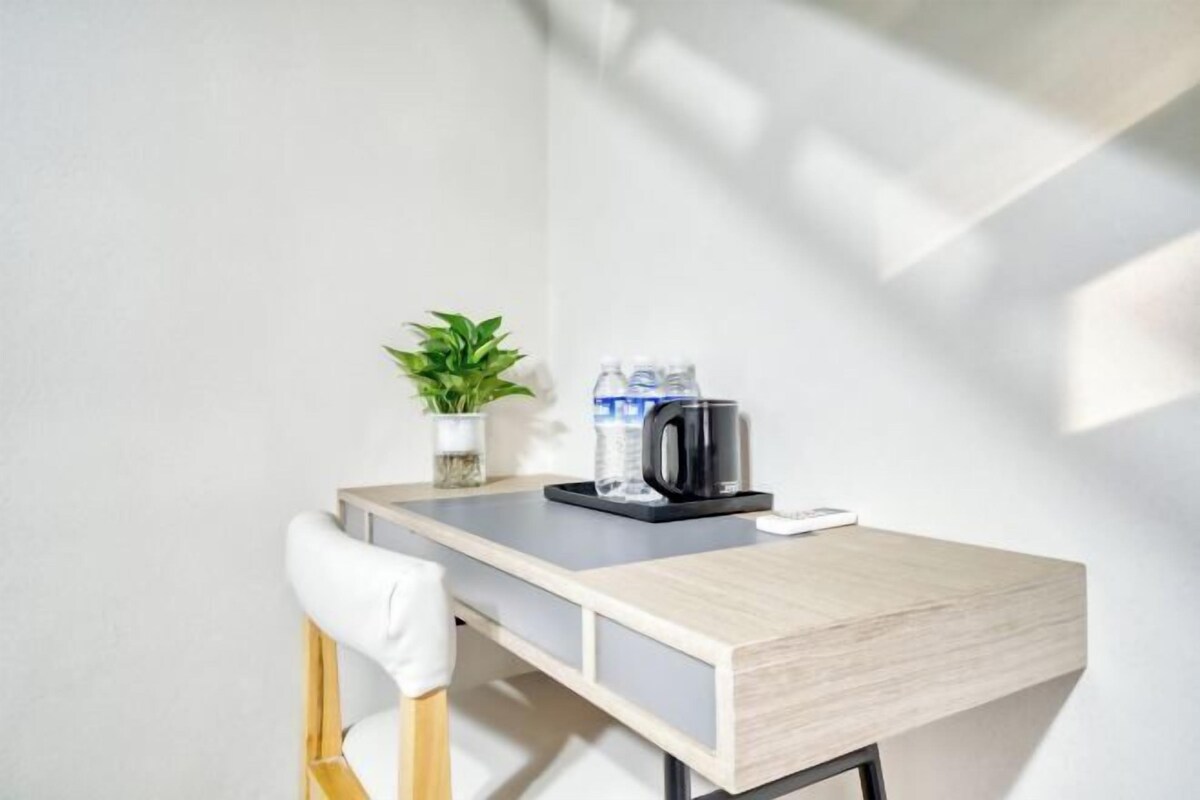 A modern desk with a plant, a water bottle, and a coffee maker.