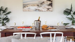 Une table à manger dressée avec des assiettes, des verres, une bouteille de champagne et un croissant.