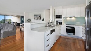 Une cuisine moderne avec des meubles blancs, des appareils en acier inoxydable et un grand îlot central.