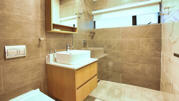 A modern bathroom with a sink, mirror, and shower.