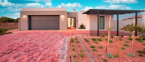 A modern house with a garage, a covered outdoor area, and a landscaped garden.
