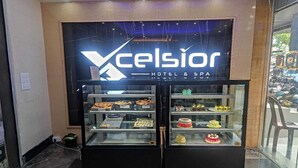 A hotel sign with 'XCelsior HOTEL & SPA' and a display case with various pastries and cakes. - XCELSIOR HOTEL AND SPA BY ROH (Shillong)