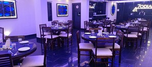 A restaurant with multiple round tables and chairs, each set with plates, cutlery, and glasses. - XCELSIOR HOTEL AND SPA BY ROH (Shillong)
