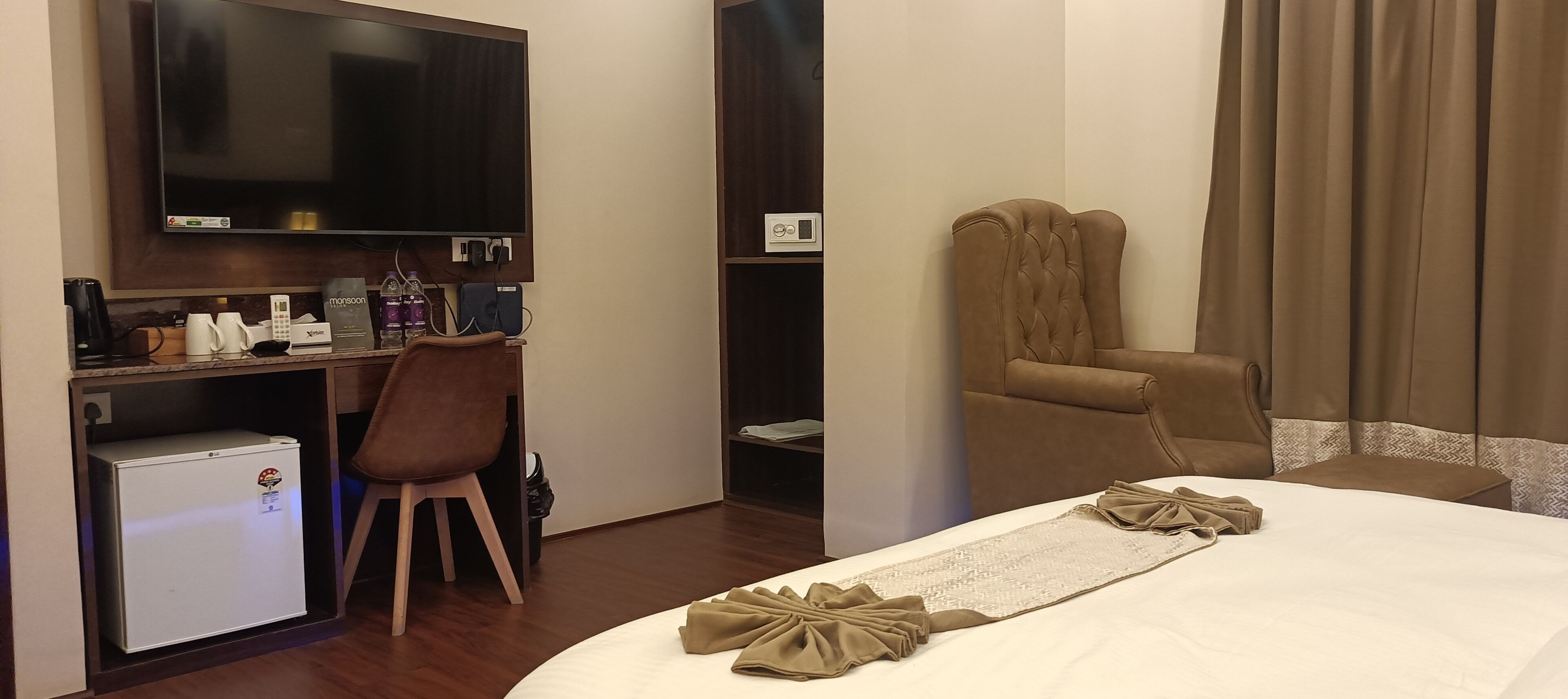 Une chambre d’hôtel équipée d’un lit, d’un bureau avec un ordinateur, d’une chaise, d’une télévision et d’un mini-bar.