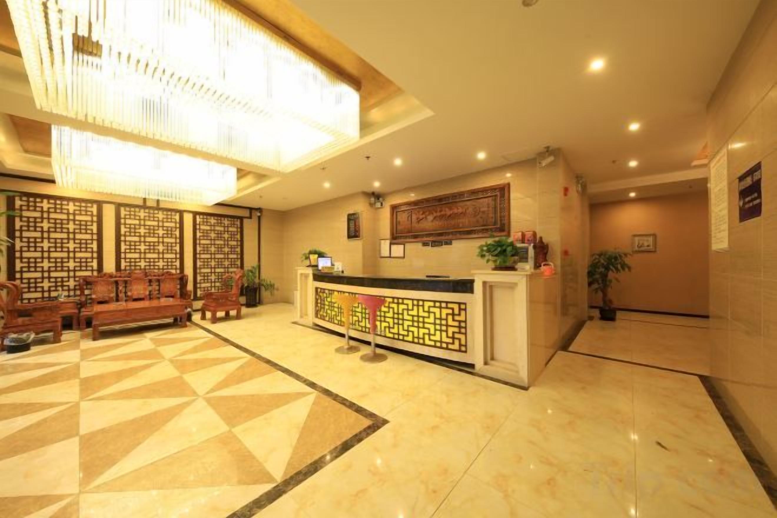 Um saguão de hotel com balcão de recepção, área de estar e parede decorativa.