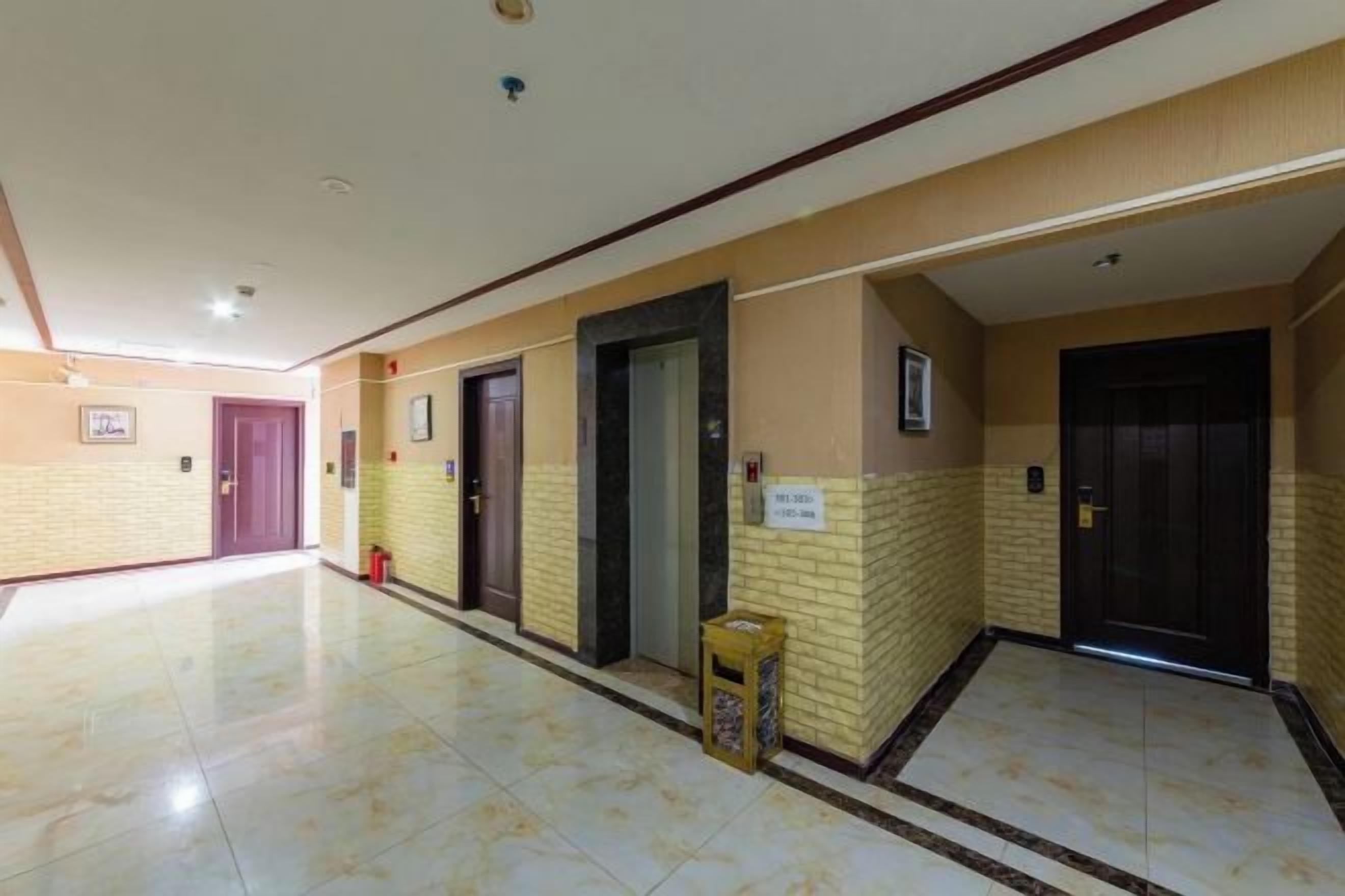 A hotel corridor with doors, a trash bin, and a sign on the wall.