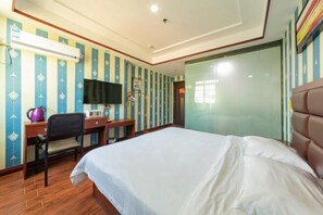 Ein Hotelzimmer mit Bett, Schreibtisch, Stuhl, Fernseher und Klimaanlage.