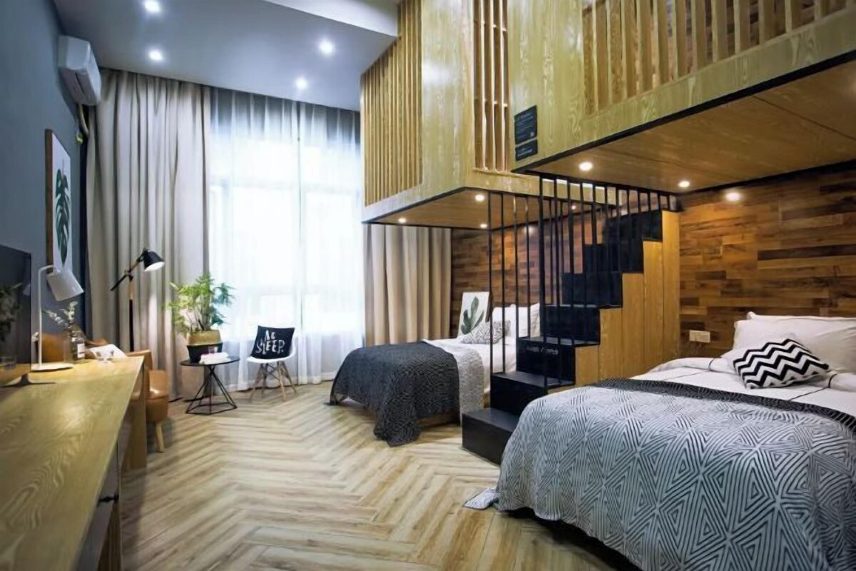 A modern bedroom with a loft area, a desk, and a large window.