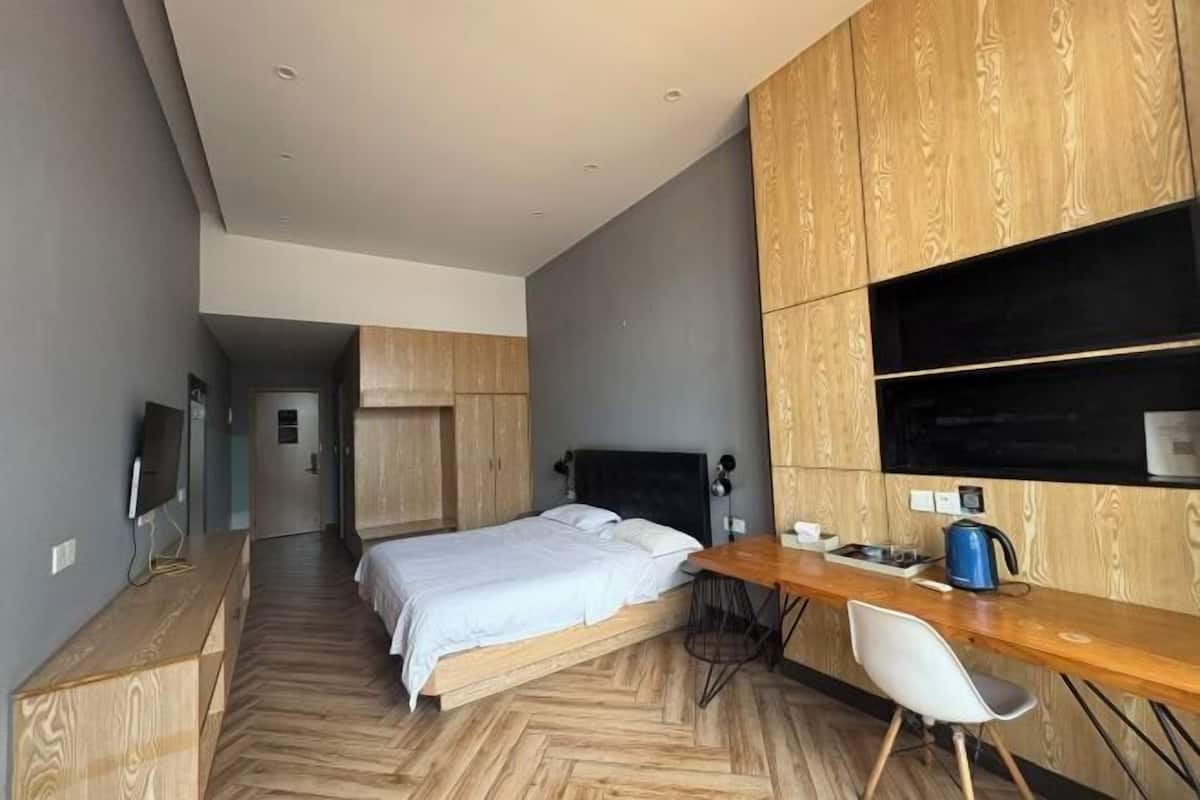 A modern hotel room with a bed, desk, and built-in wardrobe.