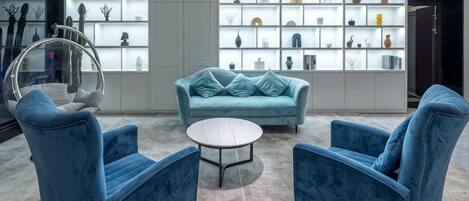 Una sala de estar moderna con un sofá azul, dos sillones azules y una mesa de centro redonda.