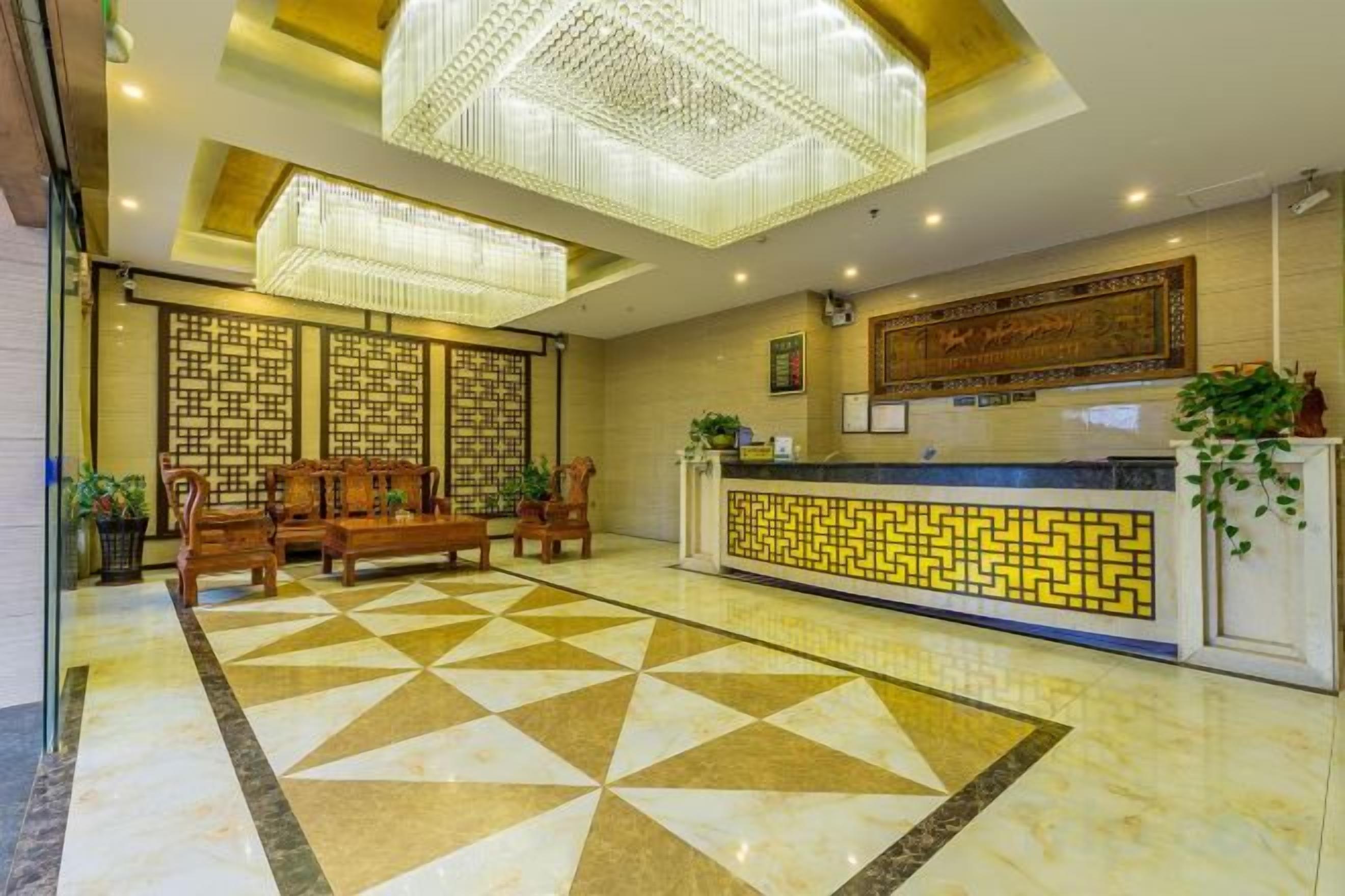 A hotel reception area with a check-in counter, seating area, and a patterned floor.