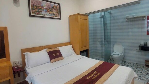 Habitación de hotel con cama, armario, zona de ducha y retrete.