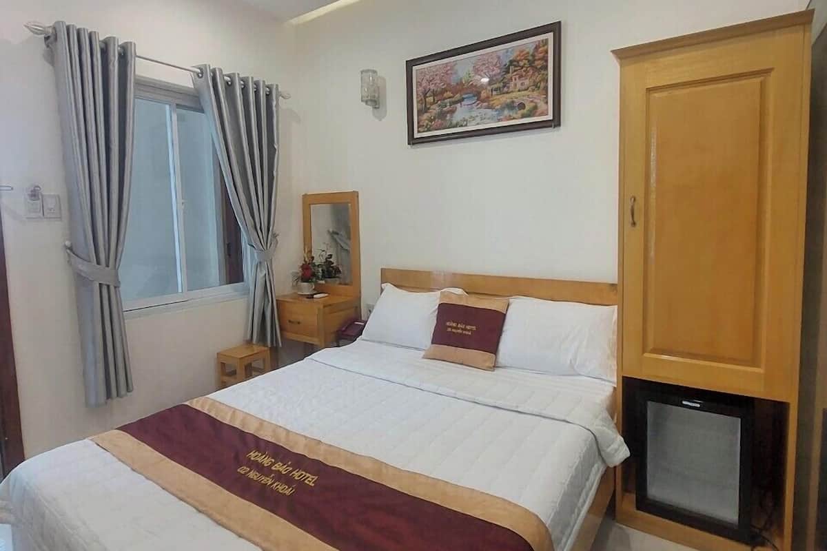 A hotel room with a bed, a nightstand, a television, a wardrobe, and a painting on the wall.