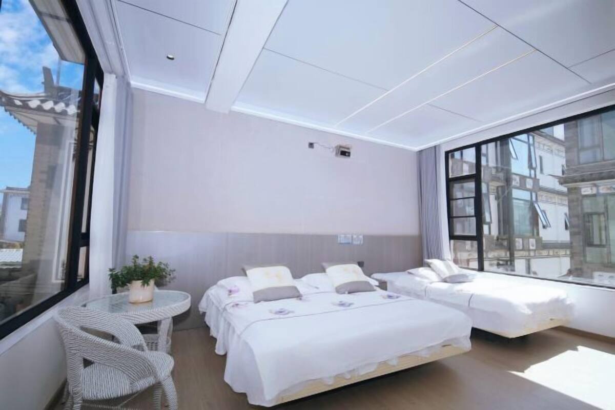 A modern hotel room with a large window, a small balcony, and a bed with a white bedspread.
