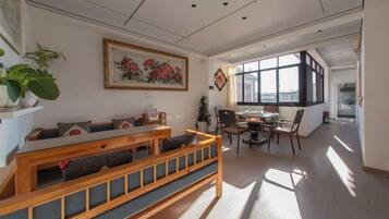 Una sala de estar moderna con un banco de madera, una mesa de comedor con sillas, un ventanal grande y un cuadro en la pared.