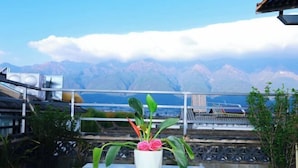 A balcony with a potted plant, a table, and a view of mountains.
