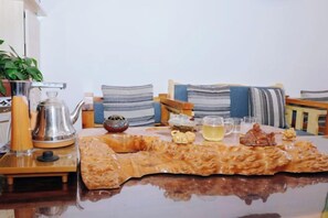 Una mesa con tetera, tazas y una bandeja de comida.
