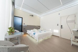 A modern hotel room with a bed, a small round table, and a chair.