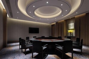 A conference room with a round table, chairs, a flat-screen TV, and a decorative vase with flowers. - YunXi DengYun Resort Hotel (Xianju)