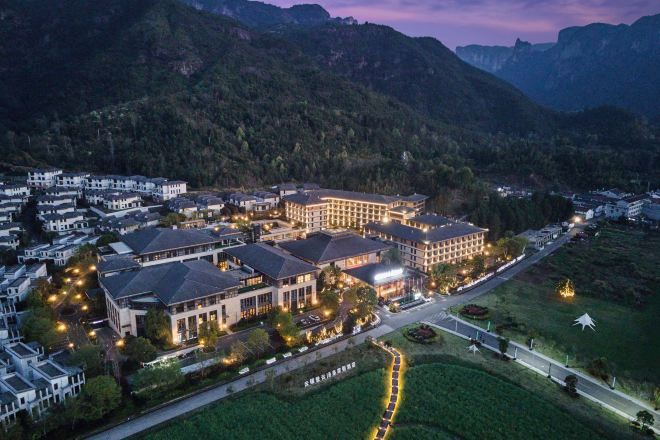 Un complejo hotelero con varias edificaciones, un césped cuidado y una carretera que conduce a la entrada.
