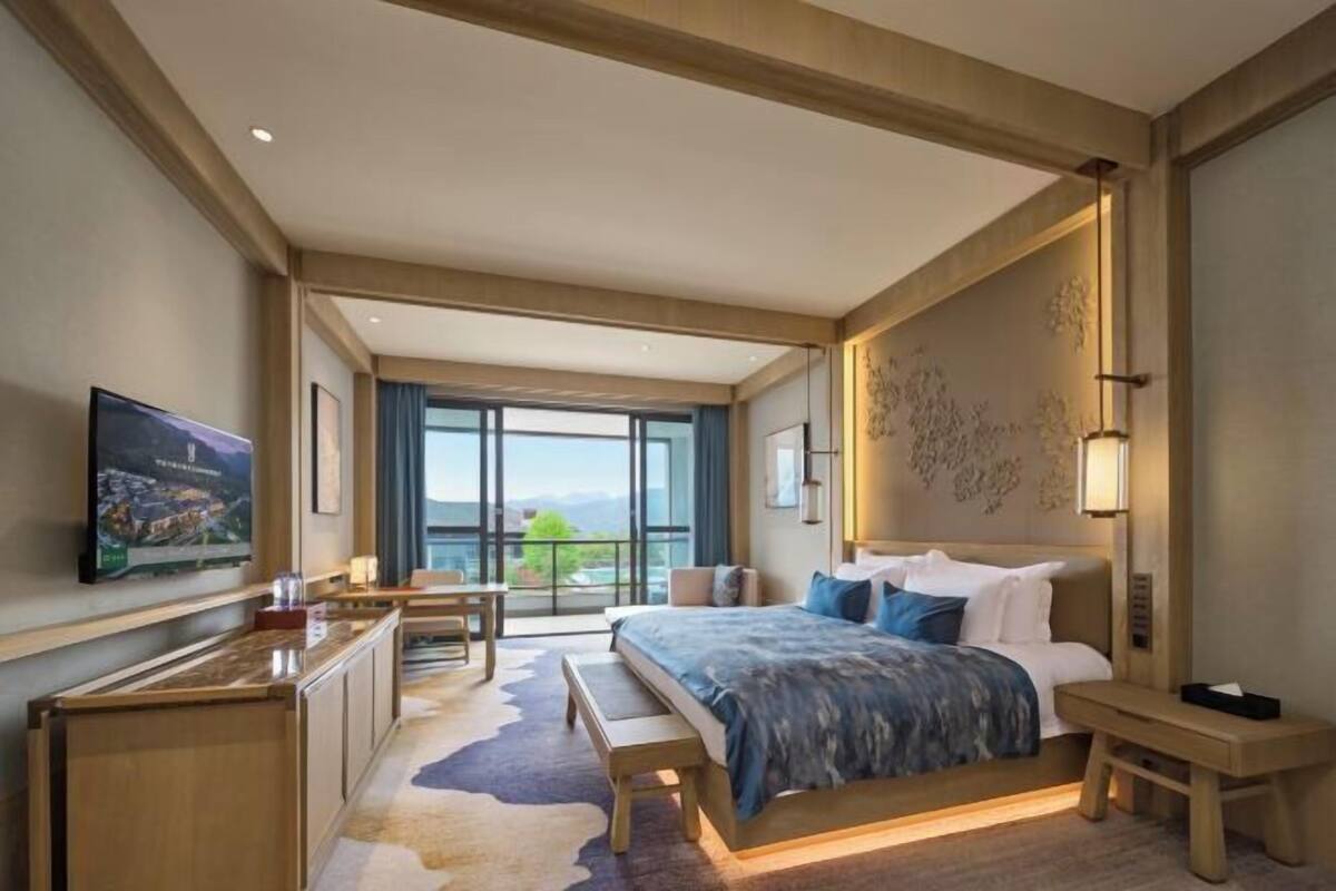 Een moderne hotelkamer met een groot bed, een bureau, een televisie en een balkon met uitzicht.