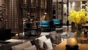 A modern interior with a seating area featuring sofas and chairs, a decorative wall with vertical elements, and a table with a candle. - YunXi DengYun Resort Hotel (Xianju)