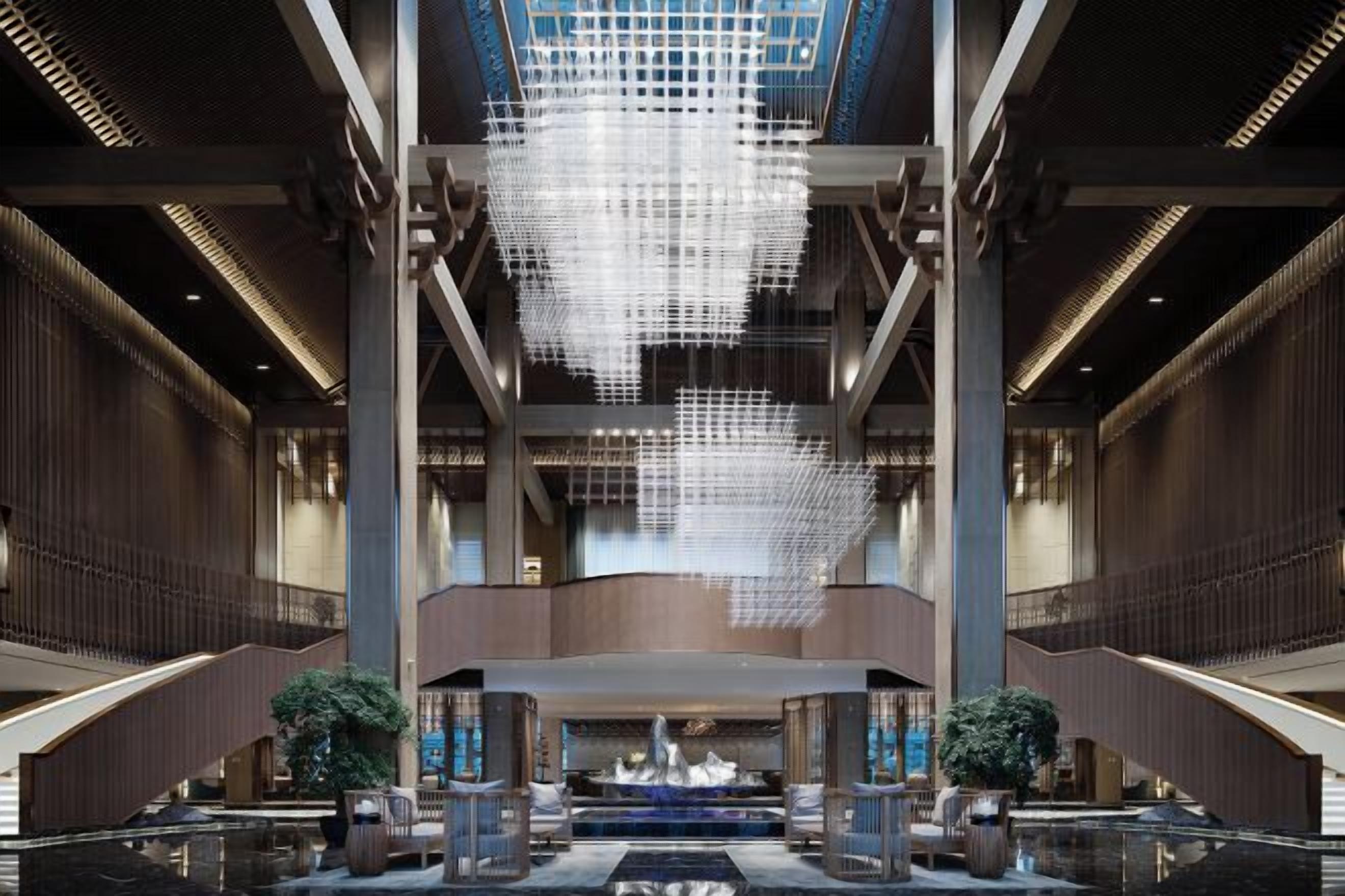 Un vestíbulo amplio con un gran candelabro, una fuente central y una escalera que conduce a plantas superiores.