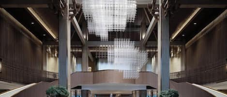 A spacious lobby with a large chandelier, a central fountain, and a staircase leading to upper levels.