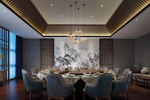 A dining area with a round table, chairs, and a chandelier.
