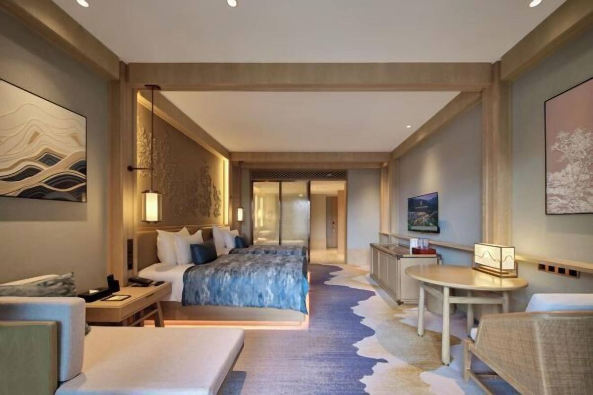 Een hotelkamer met een groot bed, nachtkastjes, een bureau en een stoel.
