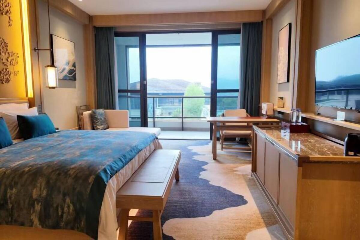 Hotelkamer met een groot bed, een bureau, een stoel, een televisie en uitzicht op de omgeving.