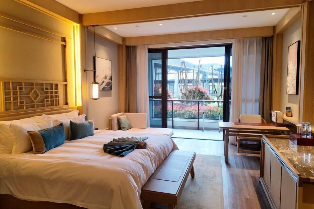 Hotelkamer met een groot bed, een bureau, een bankje en een balkon met uitzicht.