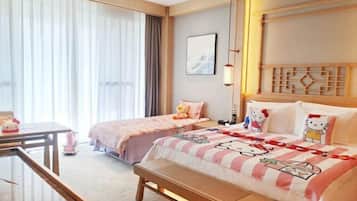 A hotel room with two beds, a desk, a bench, and a large window with curtains.