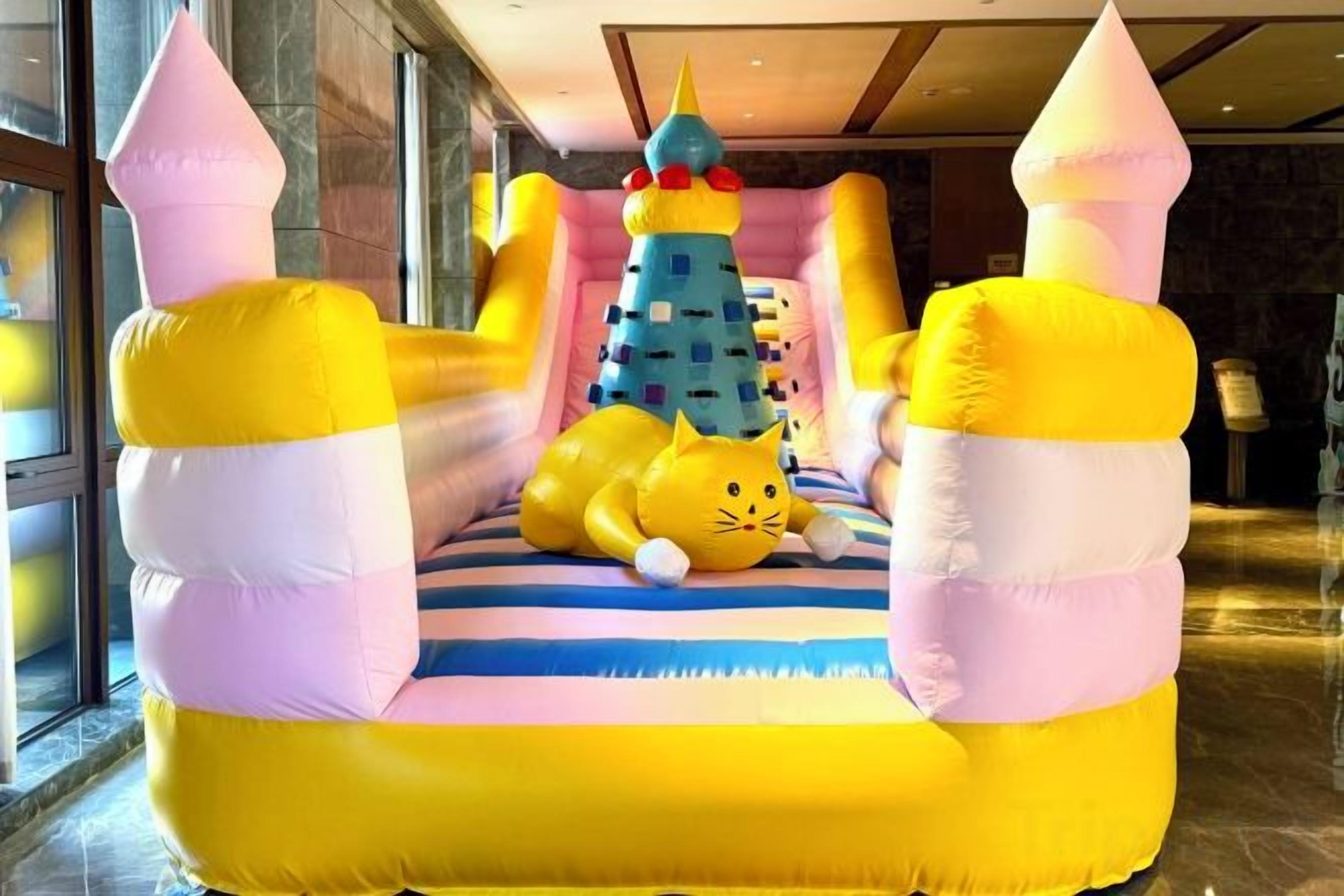 Un área de juegos inflable con un castillo, un árbol de Navidad y una figura de gato.