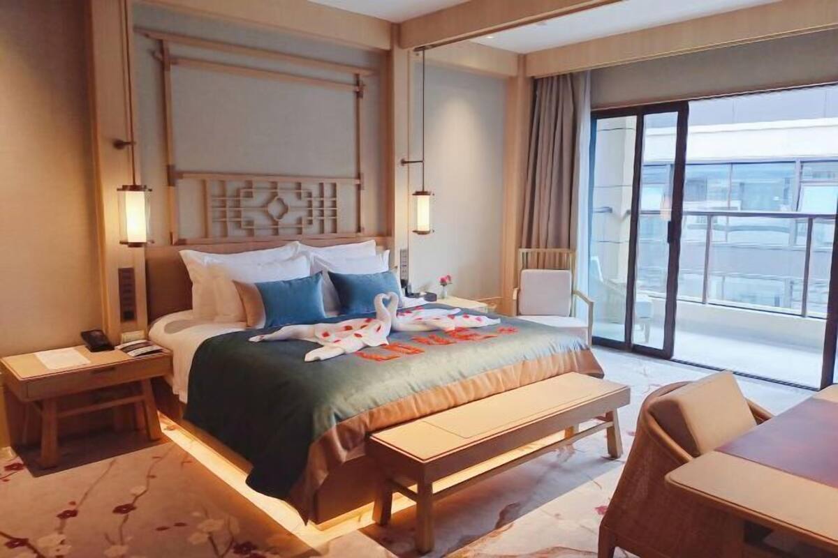 Een hotelkamer met een bed, nachtkastje, een bankje, een stoel en uitzicht.